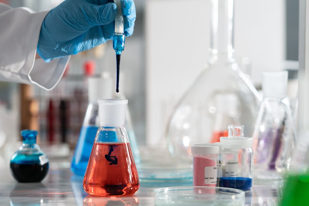 Scientist conducting a laboratory experiment with colorful chemical solutions and scientific glassware.